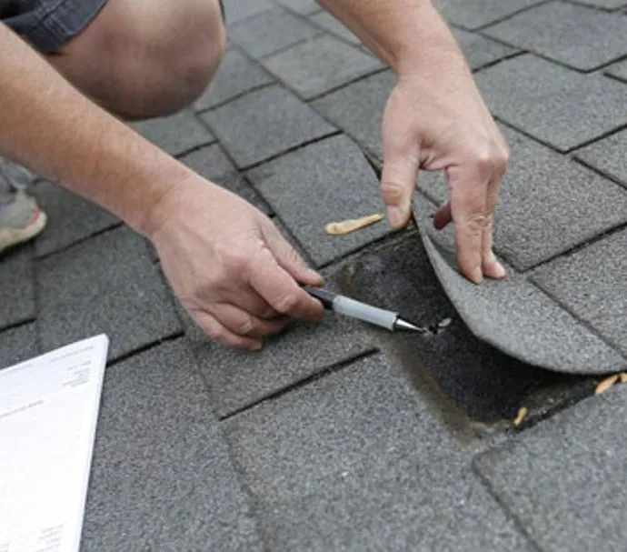 Licensed roofer performing targeted shingle repair after wind damage